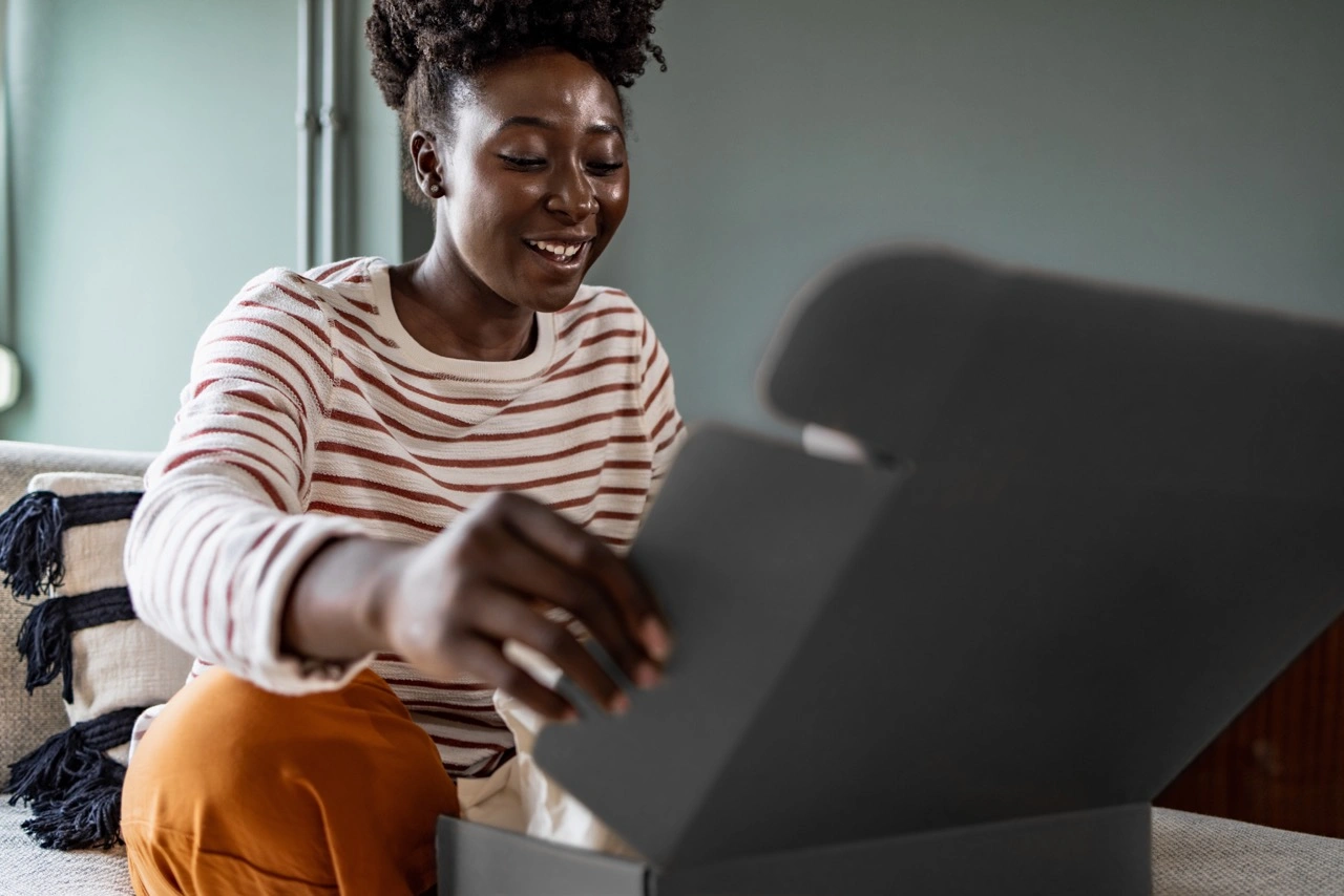 Une femme ouvre avec impatience une boîte cadeau noire